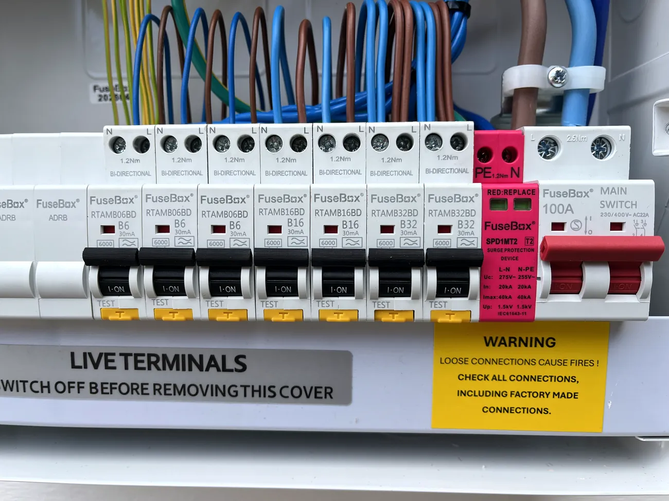 Neatly wired consumer unit terminals with combed conductors, before the cover goes back on