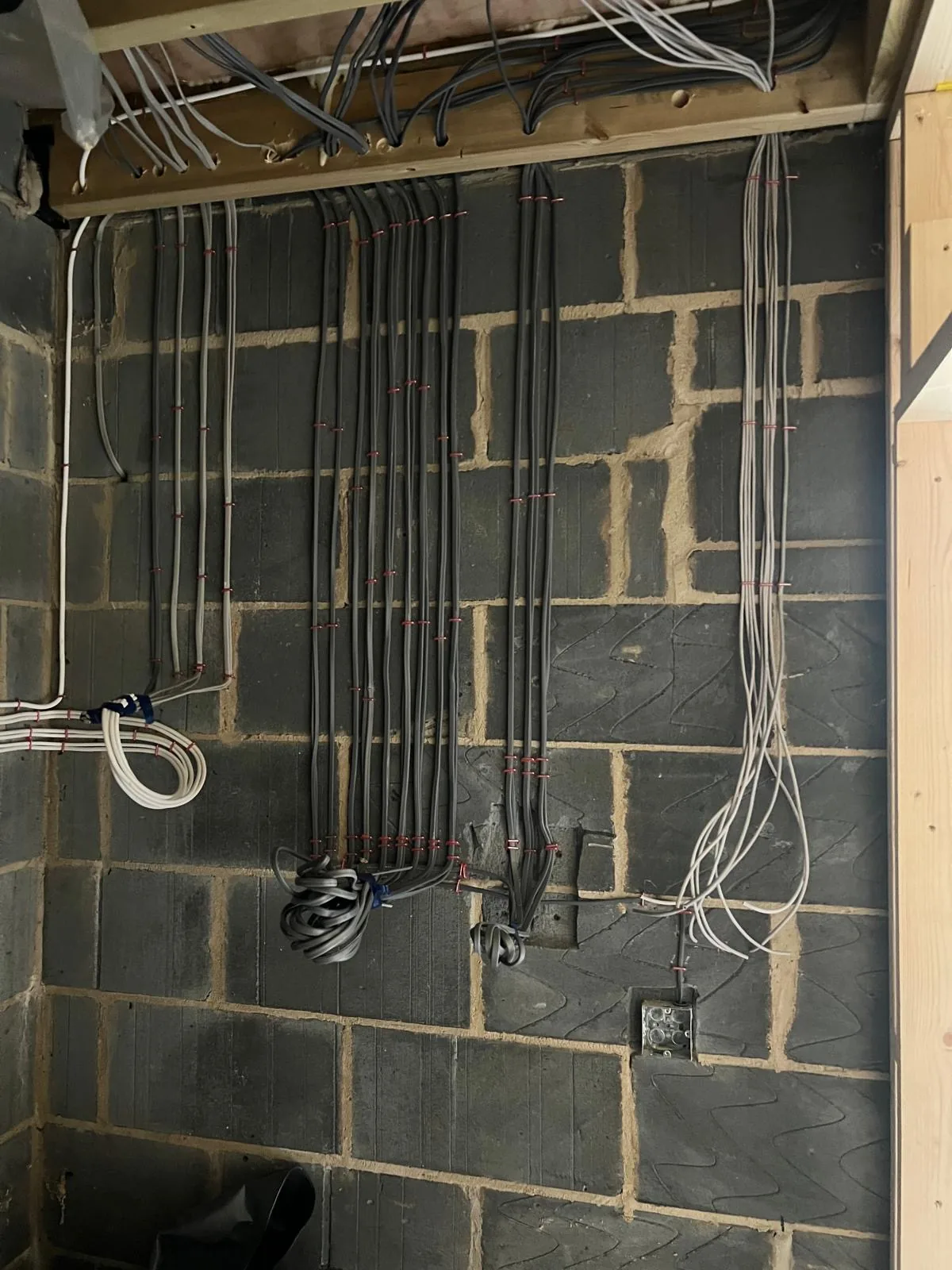 First-fix electrical wiring and back boxes run on blockwork walls in a new build, before plastering