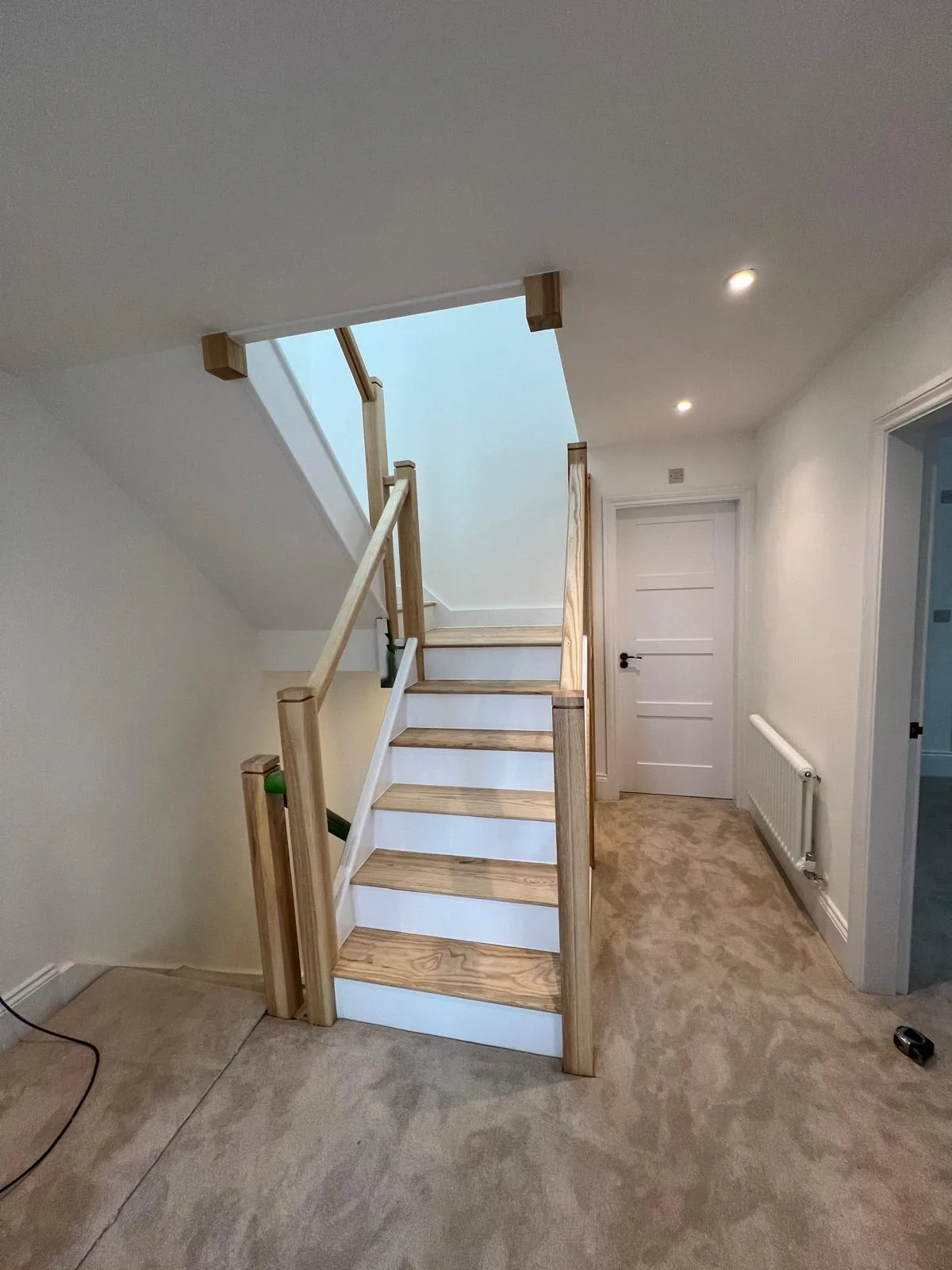Oak and glass staircase with recessed stair lighting in a finished self-build home in Poole, wired by Dorset Rewires